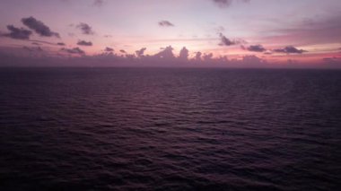Deniz manzaralı, bulutlu, kızıl bir gün batımı. Güneşin son ışınları, karanlık okyanus suyuna yansıyarak bulutları delip geçer. İHA 'nın üst görüntüsü. Mavi-beyaz gökyüzü. Phuket Sahili, Tayland