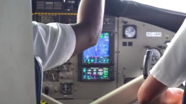 İki pilot deniz uçağını kontrol ediyor. Kabin manzarası. Farklı kollar, sensörler, düğmeler ve navigasyon ekranı. Gömlekli pilotlar uçmaya hazır. Kokpitte. Maldivler. Adalar arasında hava taksisi
