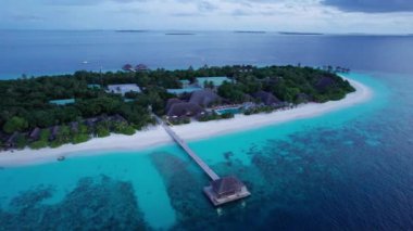 Okyanustaki bir adadan gün batımının en üst görüntüsü. Pembe renkli büyük siyah bulutlar. Turkuaz okyanus suyu, kumsalın beyaz kumu. Yeşil palmiye ağaçları ve ağaçlar. Maldivler. Su ayna gibidir.