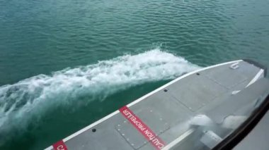 Kalkıştan önce deniz uçağının penceresinden bakın. Jet ski 'ler suyun yüzeyinde süzülür. Dalgalar ve sıçramalar oluşur. Hızlanıyoruz. Üzerinde yazı olan kırmızı bir kurdele. Basamaklar.