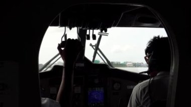 İki pilot deniz uçağını kontrol ediyor. Kabin manzarası. Farklı kollar, sensörler, düğmeler ve navigasyon ekranı. Gömlekli pilotlar uçmaya hazır. Kokpitte. Maldivler. Adalar arasında hava taksisi