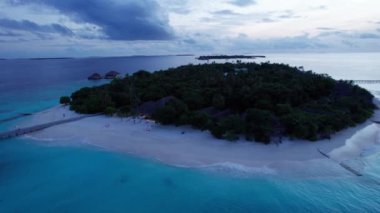 Okyanustaki bir adadan gün batımının en üst görüntüsü. Pembe renkli büyük siyah bulutlar. Turkuaz okyanus suyu, kumsalın beyaz kumu. Yeşil palmiye ağaçları ve ağaçlar. Maldivler. Su ayna gibidir.