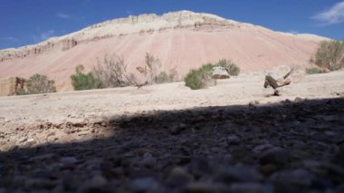 Spor ayakkabılı bir adam tebeşirle dağları aşıyor. Paleontolojik çökeltiler. Çeşitli kuru çalılar büyür, güneşin gölgeleri düşer. Mars gibi. Farklı renk ve katmanlardan oluşan dağlar.