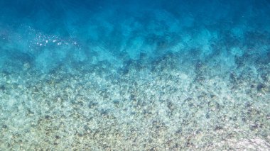 Suyun turkuaz gradyan renginin üst görüntüsü. Okyanus arka plan gibidir. Açık maviden koyu maviye inanılmaz bir değişim. Resif ve balıklar yüzer. Gölde temiz su var. İnsansız hava aracı. Maldivler