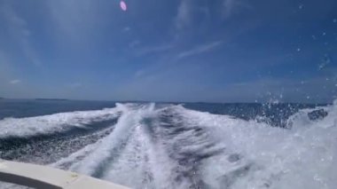 Yüksek hızlı bir teknenin motorlarından gelen dalgalar. Dikiz aynası. Mavi gökyüzü, beyaz bulut ve uzak ada. Dalgalardan beyaz köpük. Okyanusta yüzüyor. Bir sürü sprey farklı yönlere uçuyor. Açık okyanus