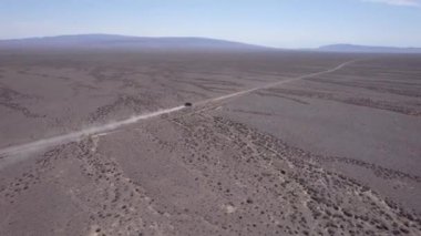 Bozkırda tozlu bir yolda siyah bir SUV hızlı gidiyor. Tekerleklerin altından ve arabanın çatısından toz bulutları uçuyor. Araba toprak bir yolun üstesinden kolayca gelir. Mavi gökyüzü ve beyaz bulutlar.