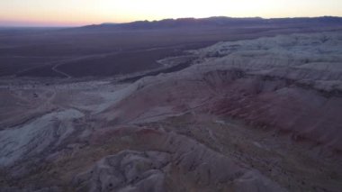 Renkli turtanın tebeşir dağları arasında gün batımı. Suyun aktığı vadinin havadan görünüşü, beyaz tepeler ve kırmızı kenarlar. Paleontolojik çökeltiler. Yükselen kayalar gibi..