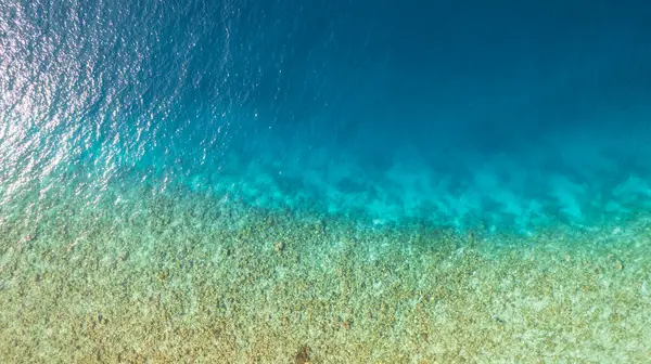 Suyun turkuaz gradyan renginin üst görüntüsü. Okyanus arka plan gibidir. Açık maviden koyu maviye inanılmaz bir değişim. Resif ve balıklar yüzer. Gölde temiz su var. İnsansız hava aracı. Maldivler
