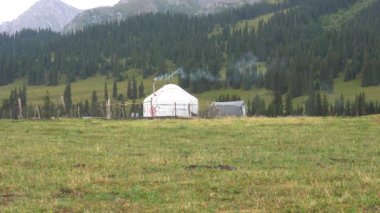 Yeşil tarlalar, dağlar ve ormanlarla çevrili bir yurt. Ocağın içinden baca dumanı çıkıyor. Çimenler sarı-yeşildir. Çitlerle çevrili geçici bir ev var. Tarım endüstrisi