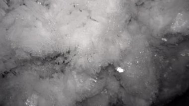 Tünel duvarında beyaz kabarık kar taneleri. Yeraltı madeni derinleşiyor, her yer buzla kaplı. Siyah borular ve kablolar donmuş. Tüneldeki karanlık, parlayan kar.