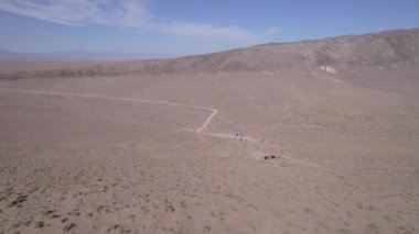 Çölün ortasında büyük bir kum tepesi. İHA 'nın üst görüntüsü. Üzerinde çeşitli kuru çalıların yetiştiği bir kum dağı. Güçlü bir rüzgar esiyor, kumu kaldırıyor. Mavi gökyüzü ve beyaz bulutlar
