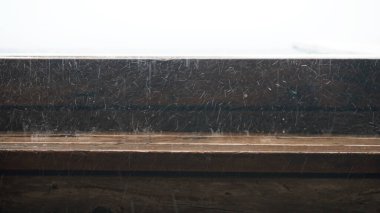 Kırsal ahşap çerçevedeki çizik pencere camının yakın görüntüsü karla örtülü sakin ve huzurlu bir atmosferi çağrıştıran sakin bir kış manzarasını gözler önüne seriyor.