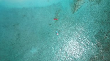 Turistlerin el değmemiş turkuaz sularda su sporlarının keyfini çıkardıkları, nefes kesen tropikal bir cennette kano ve kürek çektikleri hava manzarası.