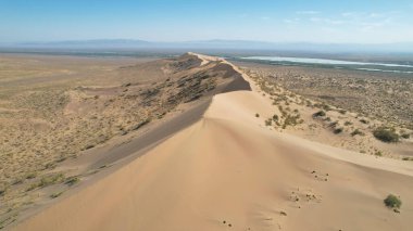 Etkileyici şarkı söyleyen Barkhan 'ın havadan görünüşü, Altyn-Emel Ulusal Parkı' ndaki büyük kum tepeciği, Kazakistan, büyüleyici bir doğa harikası yaratıyor.