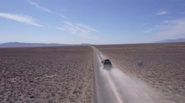 Bozkırda tozlu bir yolda siyah bir SUV hızlı gidiyor. Tekerleklerin altından ve arabanın çatısından toz bulutları uçuyor. Araba toprak bir yolun üstesinden kolayca gelir. Mavi gökyüzü ve beyaz bulutlar.