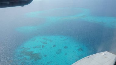 Bir uçaktan görülen kristal berrak turkuaz sudaki güzel mercan resifinin hava görüntüsü su altı ekosisteminin canlı renklerini gözler önüne seriyor.
