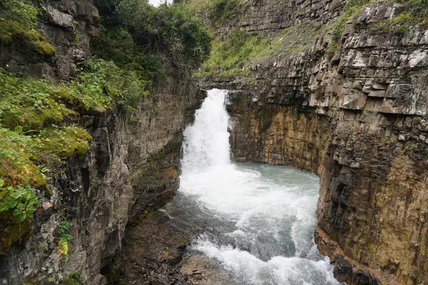 Doğal şelale kayalık bir uçurumdan el değmemiş el değmemiş bir doğa manzarası yaratan el değmemiş ıssız bir bölgedeki bir kanyona dökülüyor.