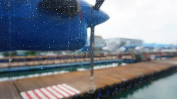 Yağmurlu bir uçak penceresinden arka planda diğer deniz uçaklarıyla birlikte tropikal bir limana bakmak tatil için bir beklenti ve heyecan hissi yaratıyor.