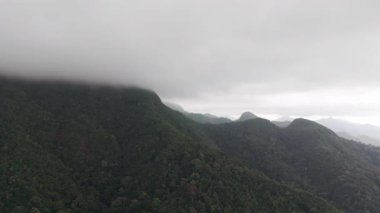 Alçak bulutlar, Koh Chang adasının canlı yeşil dağlarının zirvelerini nazikçe okşayarak el değmemiş doğal güzelliklerin büyüleyici bir manzarasını yaratıyor.