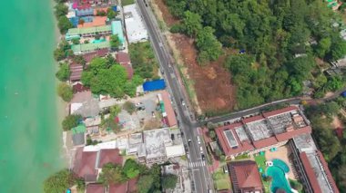 Turkuaz su, renkli binalar ve Tayland 'ın Koh Chang Adası' ndaki verimli tropikal ormanlarla çevrili canlı bir kıyı yolu etrafında yavaşça kıyıya doğru akar.