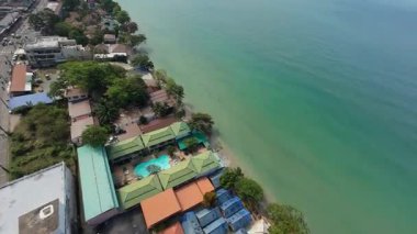 Bereketli yeşil bitki örtüsü, beyaz kumlu plajlarla ve turkuaz sularla buluşarak, pitoresk tropikal bir sahil şeridi boyunca uzanan otellerin ve otellerin büyüleyici manzarasını sunuyor.