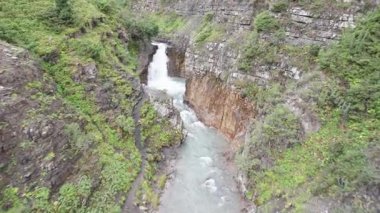 Kayaların arasında güzel bir şelale ve yeşil bir vadi. Şelalenin kenarlarında alışılmadık şekilli kahverengi taşlar var. Her yerde yeşil çalılar ve ağaçlar var. Bir İHA 'dan üst görünüm