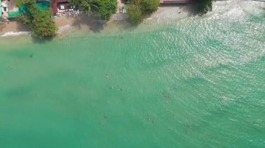 Turkuaz sular, koh chang 'ın kumlu kıyılarını nazikçe okşar. Yüzücülerin parlak güneşli gökyüzünün altında kristal berrak deniz manzarasının tadını çıkardıkları el değmemiş tropikal manzarayı ortaya çıkarır.