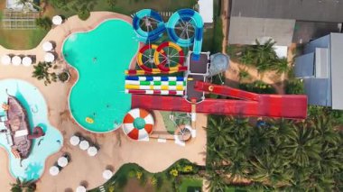 Hava manzaralı canlı su parkı renkli slaytlarla, çoklu havuzlarla, konukların palmiye ağaçları ve neşeli aile aktiviteleri arasında güneşli tropikal eğlencesiyle