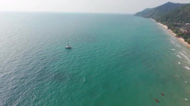 Lüks beyaz yat, sakin turkuaz sularda süzülüyor. Sade okyanus manzarası boyunca huzurlu deniz yolculuğunda parlak güneş ışığını yansıtıyor.