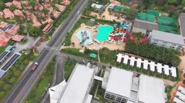 Geleneksel Tayland mimarisi, yemyeşil ve okyanusun davetkar turkuaz sularının sergilendiği el değmemiş bir sahil boyunca uzanan lüks bir tatil köyünün nefes kesici manzarası.