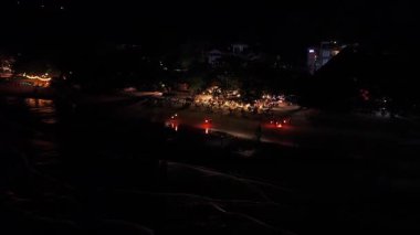 Gece sahili şenliklerinde ateş poi dansçıları parlak alevler savuruyor, karanlık kumlu kıyı şeridi ve okyanus zemininde büyüleyici ışık desenleri oluşturuyorlar.