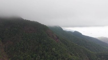 Alçak bulutlar, Tayland 'daki Koh Chang Adası' nın yemyeşil yağmur ormanlarını yavaş yavaş kaplıyor ve arka plandaki turkuaz denizi gözler önüne seriyor.
