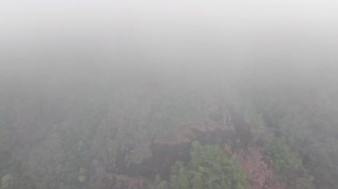 Alçak asılı bulutlarla kaplı Koh Chang adasında yemyeşil dağ zirvesi sisli, sakin atmosferik koşullarla dolu ruhani tropikal bir manzara yaratarak yemyeşil yağmur ormanları bitki örtüsünü ortaya çıkarıyor.