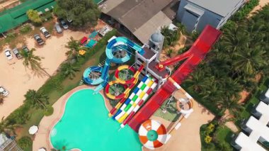 Yüksek slaytlı ve yüzme havuzlu bir su parkı. Tahttan parlak renkli slaytlara ve turkuaz su havuzuna kadar en üst manzara. İnsanlar yüzer, ata biner ve oynar. Her yerde ağaçlar ve palmiye ağaçları var.