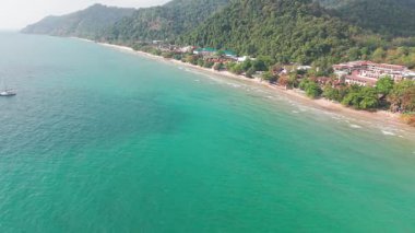 Turkuaz sular, yemyeşil tepelerin arasına kurulmuş tropikal bir sahil beldesinin kumlu sahillerine nazikçe sarılarak muhteşem bir tatil beldesi oluşturur.