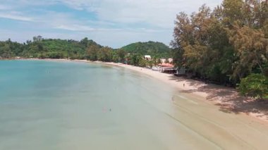 Turkuaz sularla harmanlanmış el değmemiş beyaz kumsal, yemyeşil palmiye ağaçları ve yemyeşil tropikal ormanlar tarafından çerçevelenmiş, tatil kaçamağı için huzurlu bir tropik cennet yaratıyor.