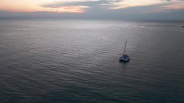 Sıcak gün batımı renkleri gökyüzünü boyuyor, katamaran sakin denizde huzur içinde süzülüyor, sakin deniz sükuneti ve egzotik bir yolculuk.