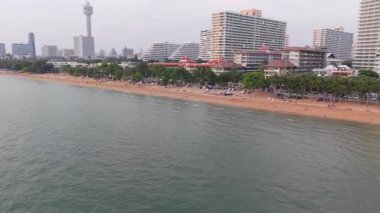 Palmiye ağaçları ve otel binalarıyla çevrili tropikal bir tatil köyünde yüzen ve havuzda oynayan turistlerin manzarası arttı.