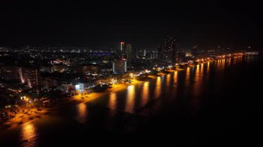 Pattaya şehir ışıkları kıyı şeridini aydınlatıyor ve geceleri su yüzeyine yansıyarak ikonik Pattaya gözlem kulesini gösteriyor.