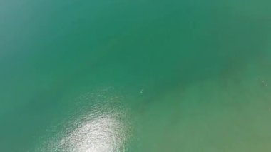 Koh Chang adası tropikal plajı ve turkuaz su tatil beldeleri, beyaz kum, yeşil orman ve arka planda dağlar ile güneş yansımasını gösterir.
