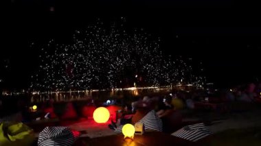 Turistler geceleri plajda bir ateş gösterisinin keyfini çıkarıyorlar. Küçük masaların etrafında minder koltuklarda rahat bir şekilde oturuyorlar. Parlayan küresel lambalarla, büyüleyici bir atmosfer yaratıyorlar.