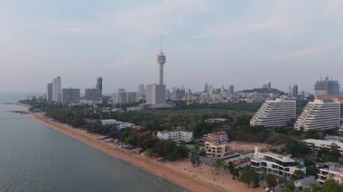 Sıcak akşam ışığı Pattaya şehir manzarasını yıkıyor, modern binalar, yemyeşil yemyeşil ve kumlu plajların ortasındaki önemli Pattaya gözlem kulesini vurguluyor.