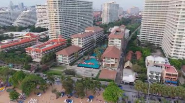Palmiye ağaçları ve otel binalarıyla çevrili tropikal bir tatil köyünde yüzen ve havuzda oynayan turistlerin manzarası arttı.