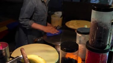 Gece pazarı temizleme ve krep yapmak için fırın hazırlama, muz, çikolata parçaları ve renkli parçacıklar gibi çeşitli malzemeler hazır.