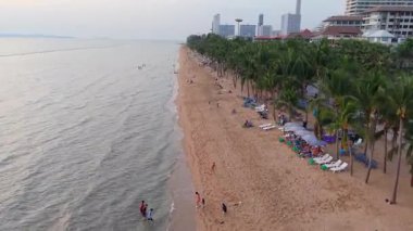 Canlı Pattaya plajı turistlerle doludur altın gün batımının keyfini çıkarırlar, kumlu kıyılarda uzanırlar ve Tayland körfezinin ışıltılı tropikal sularında yüzerler.