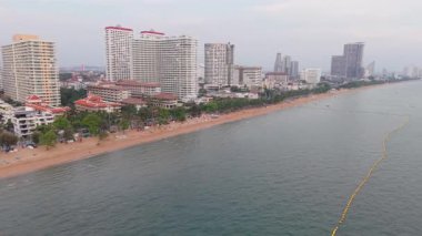 Canlı Pattaya plajı turistlerle doludur altın gün batımının keyfini çıkarırlar, kumlu kıyılarda uzanırlar ve Tayland körfezinin ışıltılı tropikal sularında yüzerler.