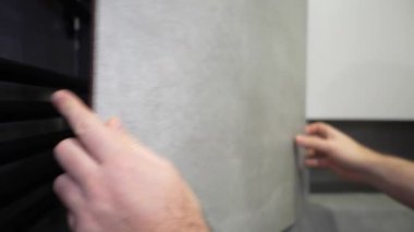 Profesyonel müteahhit, banyo duvarına modern siyah havlu ısıtıcısının yanına büyük gri bir porselen seramik yerleştiriyor ve yenileme projesinin son rötuşlarını tamamlıyor.