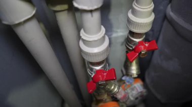 Kamera, gri ve beyaz borulara bağlı iki su sayacına yavaş yavaş yaklaşıyor ve yerleşim tesisatına daha yakından bakmamızı sağlıyor.