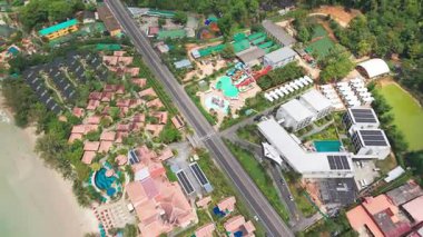 Havuz, bereketli palmiye ağaçları, güneş paneli teçhizatlı çatılar ve el değmemiş havuz kenarı dinlenme alanlarının yer aldığı lüks tropikal tatil beldelerini gözler önüne seren hava manzarası.