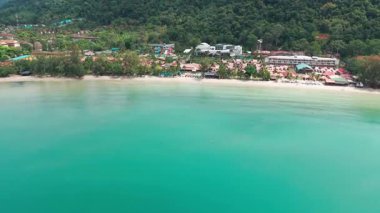 Turkuaz su, yemyeşil bitki örtüsü arasında yerleşmiş bir tatil köyü ile tropikal bir plajın kıyısına usulca uzanır. Huzurlu ve davetkar bir kaçış sunar.